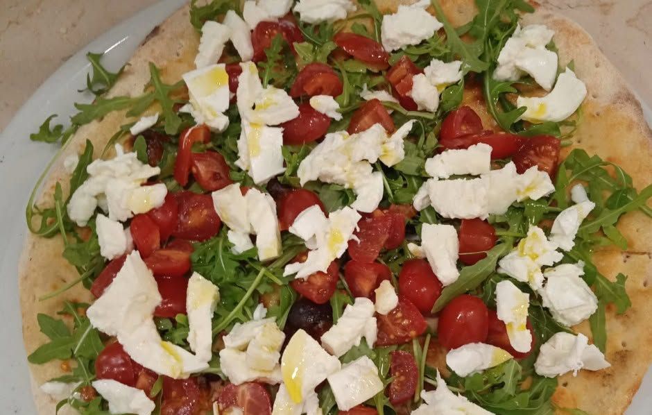 Pizza con pomodorini, rucola e pezzetti di formaggio fresco