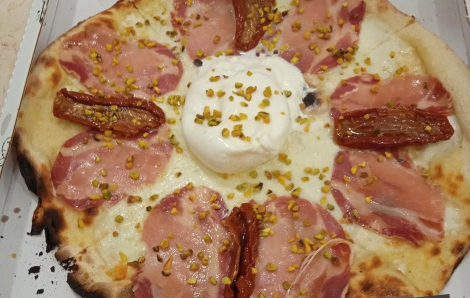 Pizza con burratina al centro, salumi, pomodori secchi e granella di pistacchio